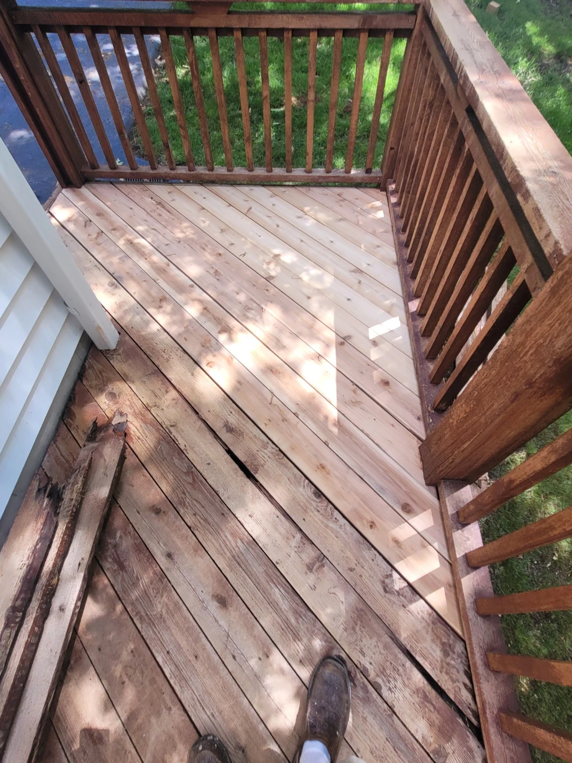 New deck boards replacing deteriorated boards beside existing railing