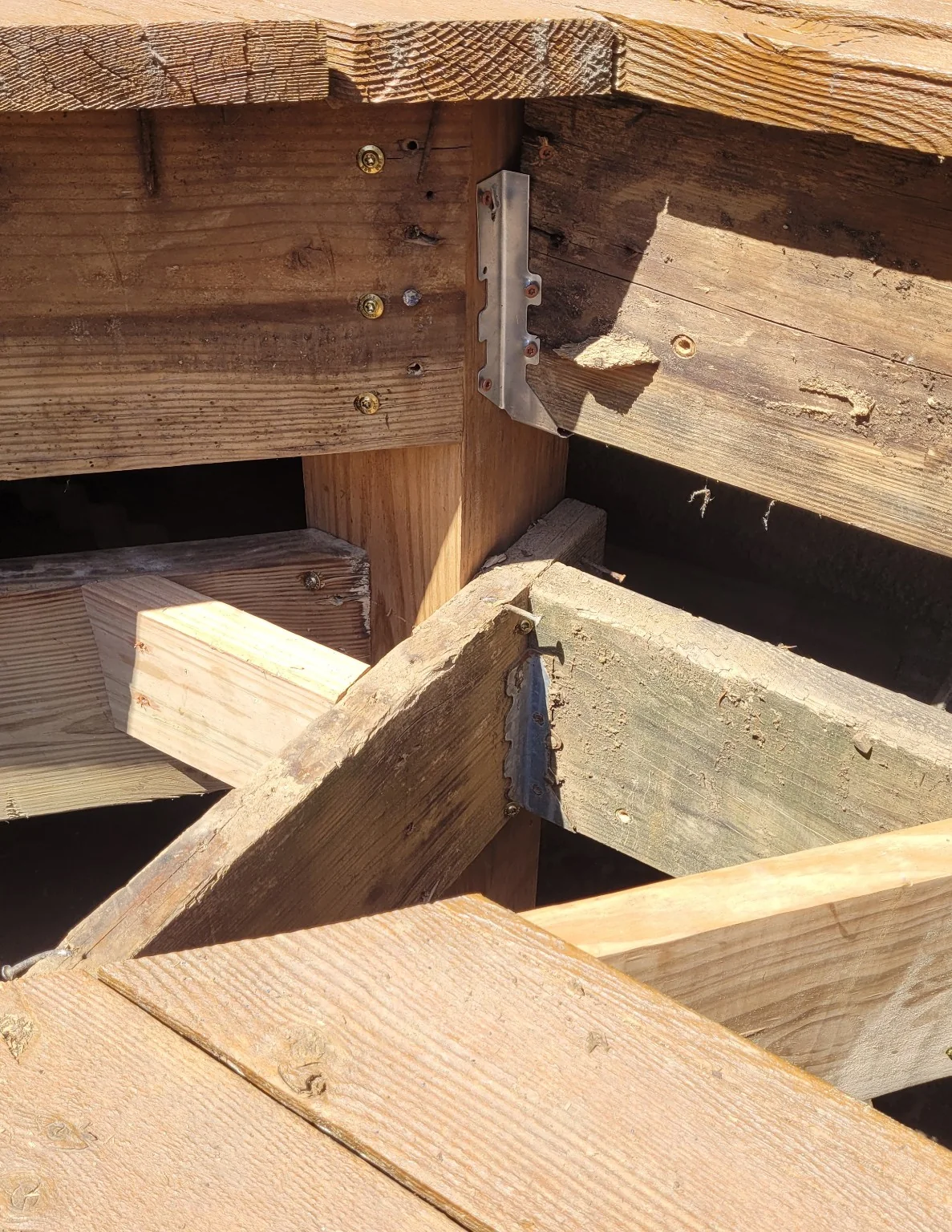 Structural support repair beneath wraparound deck step showing repaired framing connections